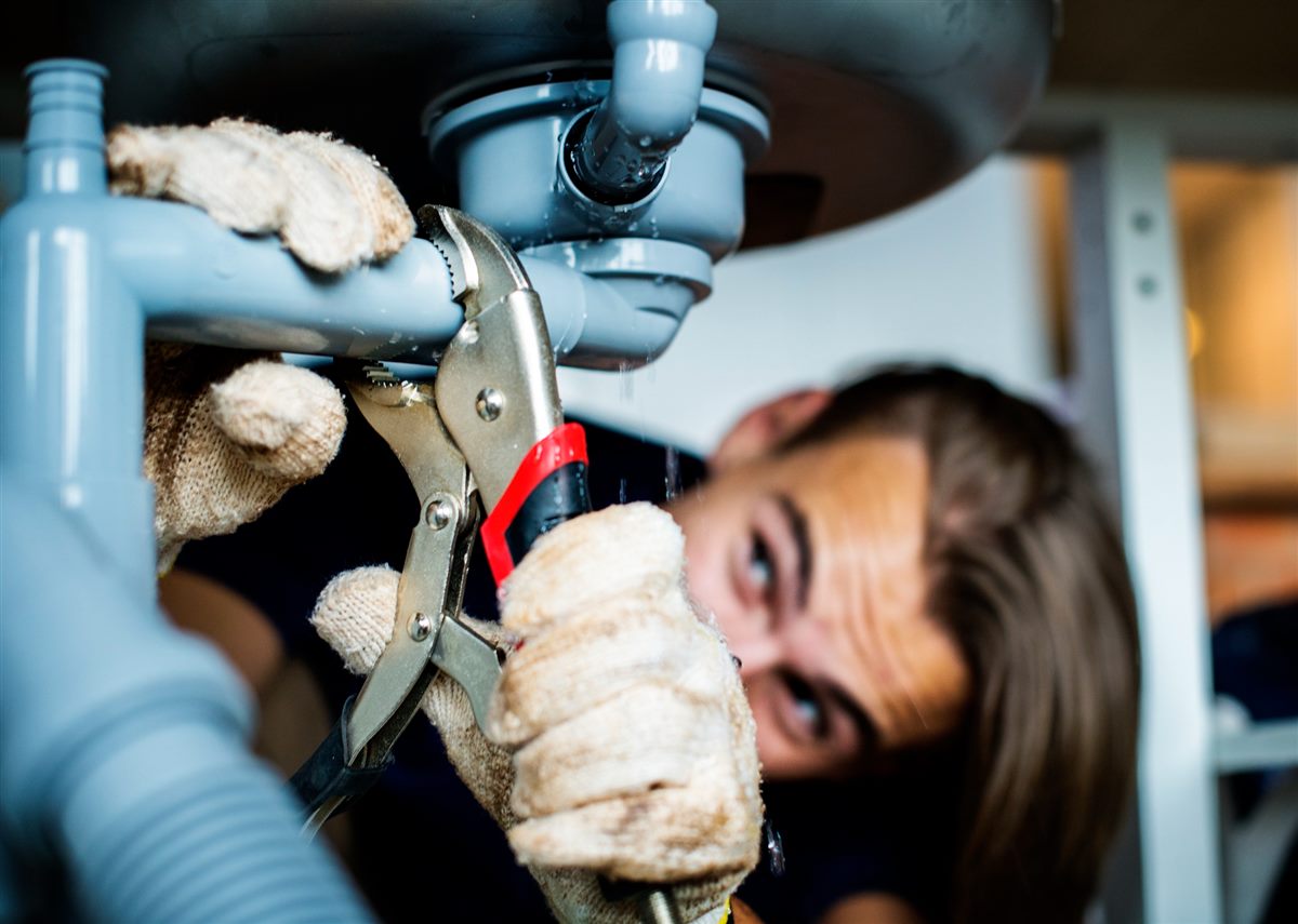 Plumber tightening a pipe fitting under a sink